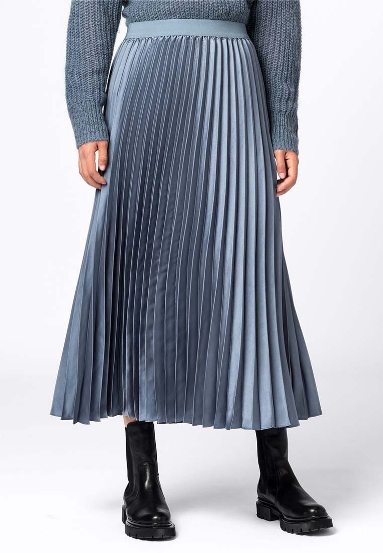 Plissé midi kjol i en gradient från ljus till mörk blå satin, med ett brett midjeband. Bärs med svarta ankelstövlar.