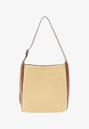 Beżowa pleciona torba ze słomy z gładką brązową skórzaną podstawą i paskiem na ramię. Posiada kwadratowy kształt i kontrastowe szwy.