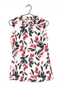 Haut sans manches à imprimé floral avec un col à volants, présentant des fleurs rouges et noires sur fond blanc. Tissu léger, avec une coupe décontractée.