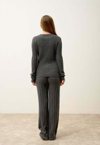 Szary, prążkowany top z długim rękawem i okrągłym dekoltem, w zestawie z dopasowanymi, prążkowanymi spodniami szerokimi. Gładka tekstura, dopasowany krój.