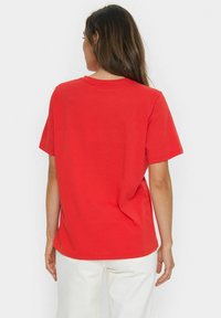 Red cotton t-shirt with a round neckline and short sleeves. Features a relaxed fit and a smooth texture, displayed from the back.