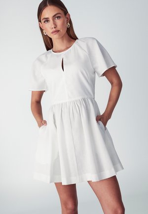 Biele šaty s krátkym rukávom a okrúhlym výstrihom, so predným výrezom, elastickým pásom a bočnými vreckami. Hladká látka s voľnou sukňou.