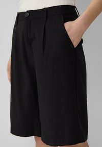 Schwarze, plissierte Shorts aus weichem Stoff mit Seiten taschen und Knopfverschluss, im lässigen Schnitt und knielanger Länge.