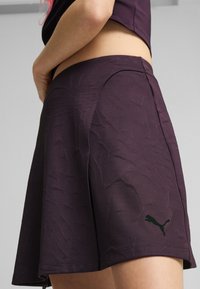 Lilla sportkleit tekstureeritud mustriga, külglibisega ja musta Puma logoga hemperis. Valmistatud elastset ja hingavat materjalist.