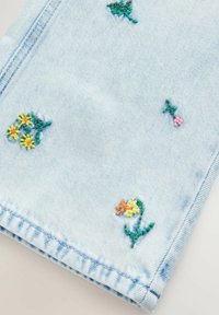 Lyseblå denimstof med små broderede blomster i gul, orange, pink og grøn spredt hen over fladen nær kanten.