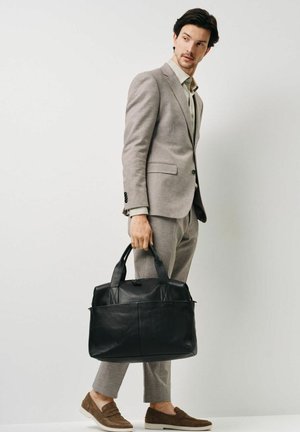 Czarna skórzana torba tote z solidnymi uchwytami, charakteryzująca się teksturowanym wykończeniem i zamknięciem na zamek. Torba ma wyraźny kształt i minimalne akcenty.