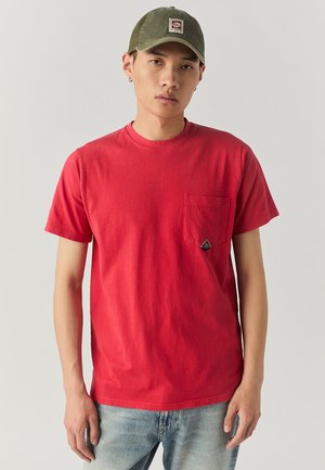 T-shirt in cotone rosso con scollatura rotonda, maniche corte e taschino sul petto. Presenta un piccolo logo triangolare vicino al taschino.