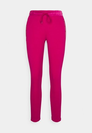 Lyserøde, slanke joggingbukser med elastisk talje og snøre, med lynlåslommer i siden.
