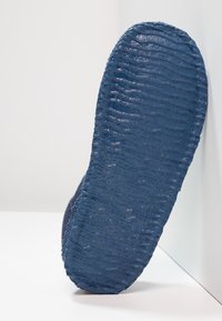 Blauwe gestructureerde zool met een golvend patroon; rubbermateriaal. Zijaanzicht dat de dikte en het gripdetail van de zool toont.