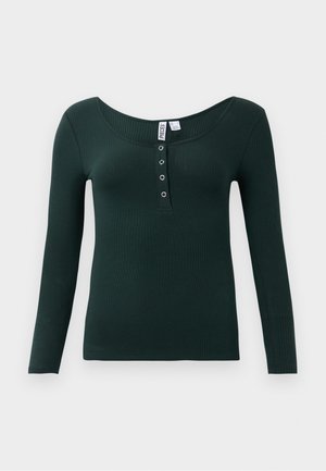 Chemise à manches longues côtelée vert foncé avec un décolleté en scoop et quatre boutons-pression en métal sur le rabat avant.