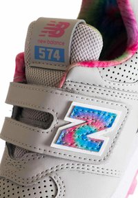 Sneaker grigio con pelle perforata, pannello in rete, logo "Z" con gradiente colorato e accenti rosa sul colletto e sulla suola. Modello 574.