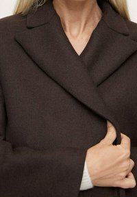 Brown wool blend coat with a notched collar, tailored fit, and deep front closure. Soft texture and warm appearance.