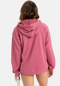 Różowy polarowy hoodie z dużym kapturem, długimi rękawami i luźnym fasonem. Miękka struktura z ribbowymi mankietami i dołem.