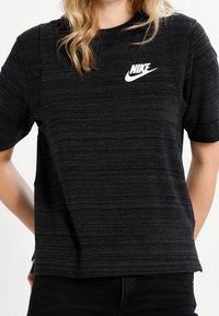 Svart kortärmad T-shirt i texturerad tyg med rund hals; har en vit Nike-logotyp på bröstet.