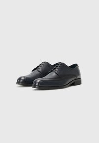 Navy leather dress shoes with a rounded toe, smooth texture, lace-up design, and a low, wooden heel. Subtle stitching detail along the sides.