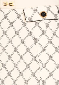 Tessuto bianco con un motivo geometrico nero caratterizzato da forme rettangolari, accentuato da una chiusura dorata e un bottone nero di lato.