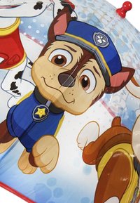Paraplu van een speelse, cartoonachtige hond in een blauwe politie-uniform met een badge, tegen een lichtblauwe achtergrond met stippen. Rode handgreep.