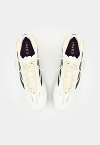 White soccer cleats with black stripes, round toe, and textured surface. Laces are light beige with a purple insole featuring "COPA."