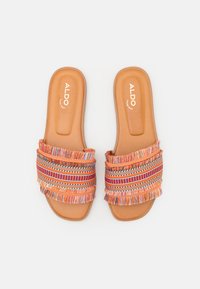 Oranga slide-sandaler med vävda tygremmar som har flerfärgade fransar och dekorativa mönster. Slät tan färgad fotbädd med logotryck.