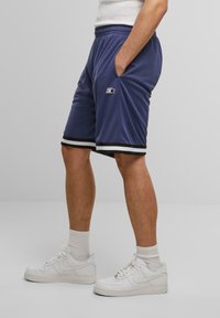 Shorts de sport navy avec des bordures blanches et noires, fabriqués en tissu lisse. Ils présentent une taille élastique et des poches latérales pour plus de praticité.
