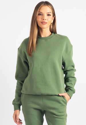 Zielona bluza wykonana z miękkiego materiału, z okrągłym dekoltem, długimi rękawami i luźnym krojem. W zestawie z dopasowanymi spodniami.