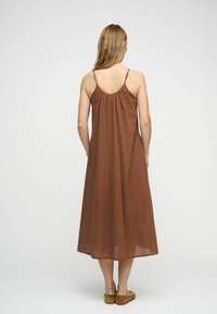 Rochie maxi fără mâneci, de culoare maro, cu un spate pliat, realizată dintr-un material ușor, având bretele subțiri și o croială lejeră.