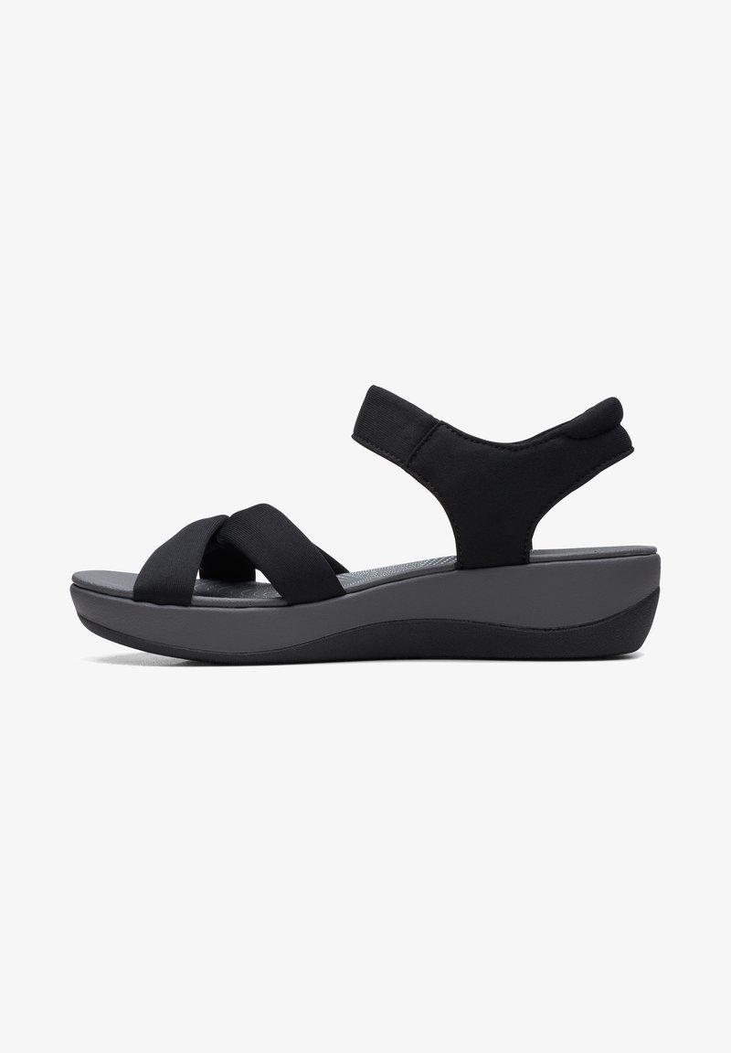 Sandale noire avec semelle grise rembourrée, larges brides croisées sur les orteils et bride de cheville rembourrée avec fermeture Velcro.