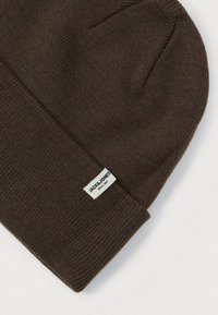 Brązowa dziana czapka z wywijanym brzegi i małą białą metką z napisem "JACK & JONES SINCE 1990" na jasnym tle.