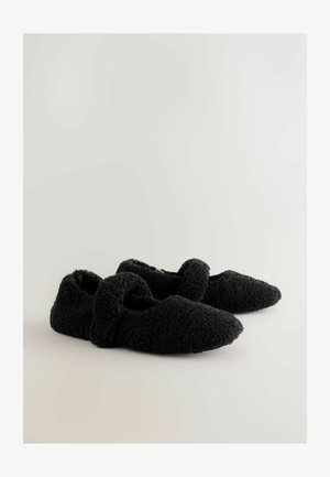 Mustad sussid valmistatud pehmest, tekstuuriga kangast, millel on terav nina ja kaardus pealmine rihm, mis tagab kindla istuvuse.