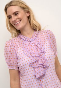 Helllila Bluse mit diamantförmigem Muster in Orange und Creme, ausgestattet mit einem gerüschten Vorderteil, kurzen Puffärmeln und Knopfverschluss.
