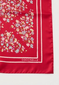 Červený hedvábný šátek s květinovým vzorem malých modrých a bílých květů. Okraje jsou orámovány bílými liniemi. Název značky: Coccinelle.