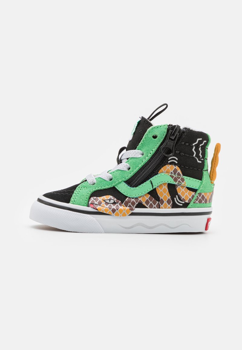 Baskets montantes noires et vertes avec des lacets blancs, une fermeture éclair sur le côté, et un motif serpent sur la semelle et la partie supérieure.