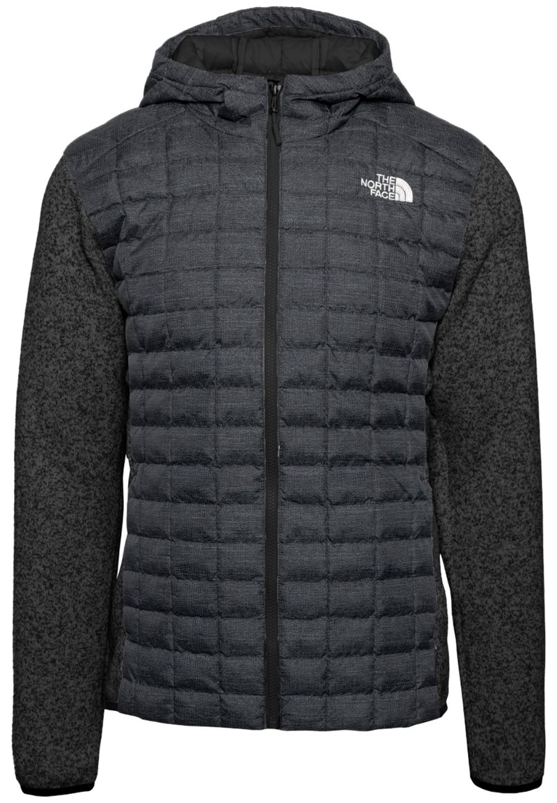 Puffjacka i mörkgrått med quiltad front, slät huva och kontrasterande texturerade ärmar. Har en svart dragkedja och logodetalj.