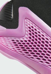 Detail obuvi s černým svrškem, růžovou průhlednou podrážkou s motivem včelího plástu a texturovanými akcenty pro lepší přilnavost.