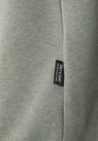 Camiseta de algodón color verde claro con superficie texturizada y una etiqueta negra en el lateral con el nombre de la marca "ONLY & SONS".