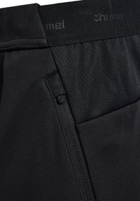 Svarta träningsshorts med en strukturerad midja, sidoficka med dragkedja och slät tygkvalitet. Har en diskret logotyp på midjan.