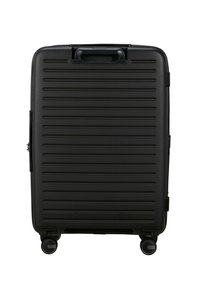 Black hard-shell suitcase with horizontal grooves, four wheels for mobility, a top handle, and a zipper closure. Smooth texture and modern design.