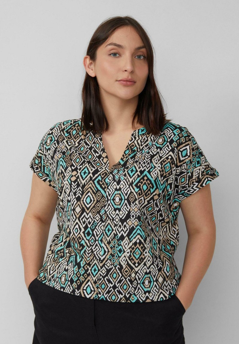 Korte mouwen blouse in een geometrisch patroon met zwart, beige, turquoise en wit. V-hals ontwerp, lichte stof en een relaxte pasvorm.