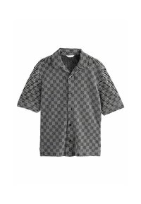 Camisa de manga corta en blanco y negro, con un patrón ondulado, cierre de botones y cuello con muesca. Fabricada con tejido ligero.