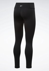 Legging de sport noir taille haute avec coutures visibles et petit logo blanc au centre du dos de la ceinture.
