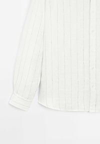 Chemise blanche à manches longues avec fines rayures verticales noires, boutonnée à l'avant avec poignets, sur fond uni.