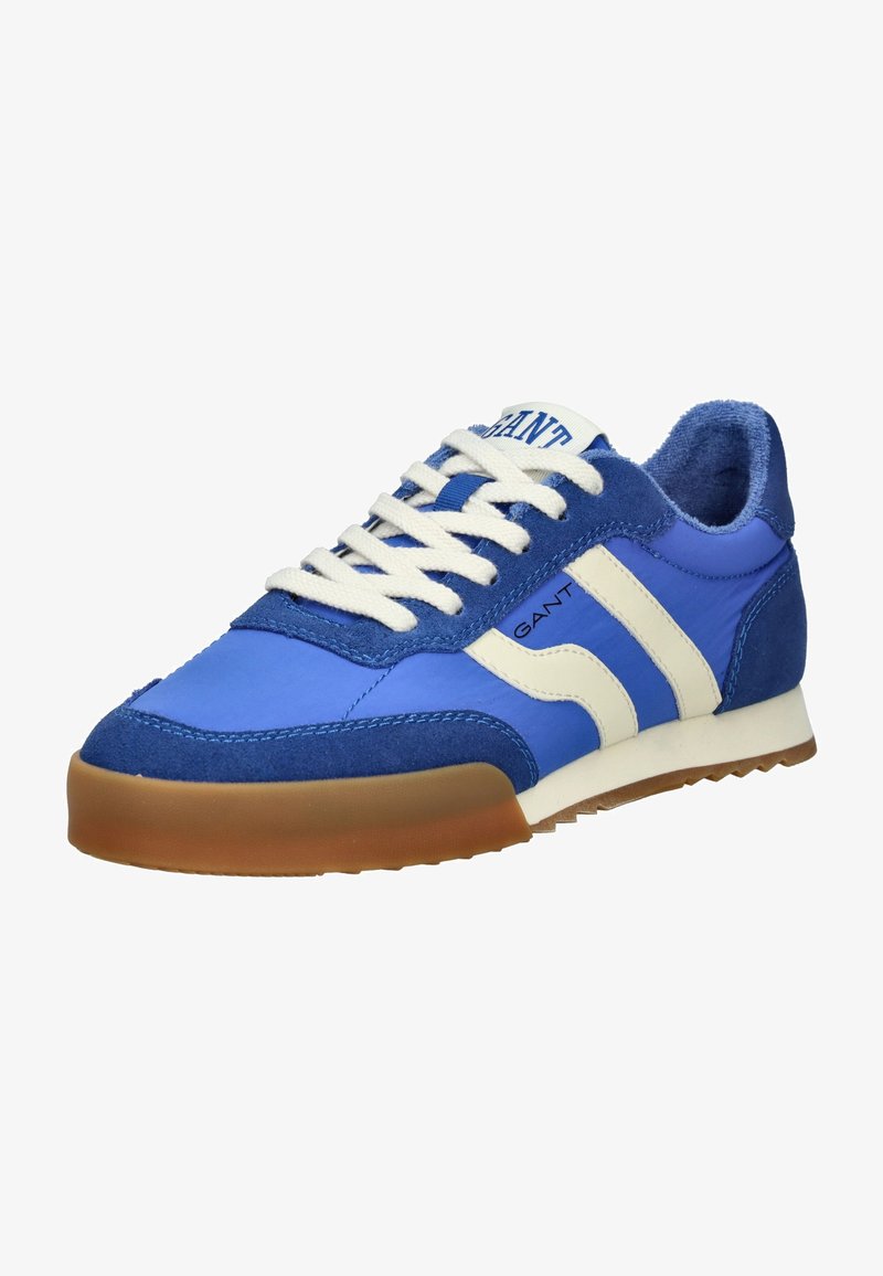Zapatilla azul con una mezcla de texturas lisas y de ante, que presenta franjas y cordones blancos, y una suela de goma marrón claro. Diseño clásico.