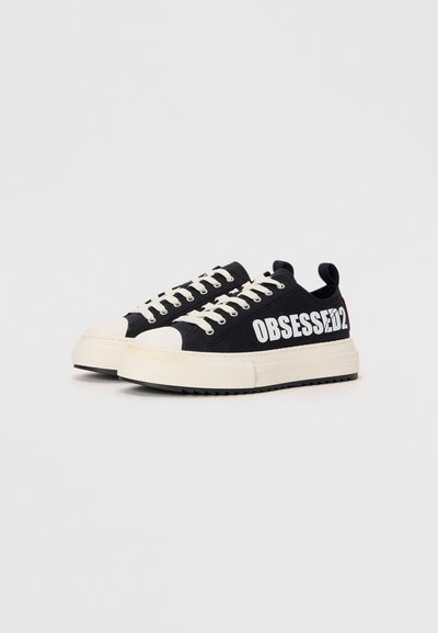 Baskets en toile noires avec le texte "OBSESSIF" en blanc, embout en caoutchouc crème et semelle intermédiaire, design à lacets et semelle noire texturée.