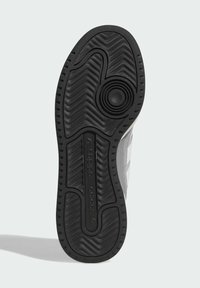 Black rubber outsole with zigzag tread pattern; incorporates a circular logo detail; features a smooth texture with a contrasting grey section.