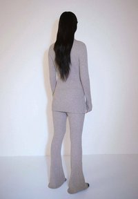Tenue en tricot côtelé gris, avec des manches longues et un pantalon évasé, dotée d'une texture lisse et d'un design ajusté, vue de dos.