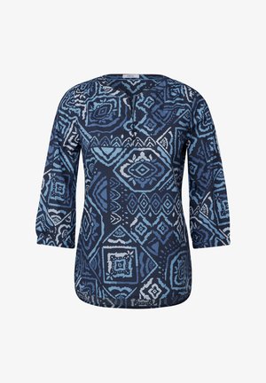 Mörkblå blus med trekvartslånga ärmar, med ett geometriskt mönster i nyanser av blått och vitt. Rund halsringning med tre knappar.