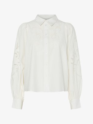 Valge nööbitav särk, millel on esipinnal ja varrukatel tikitud lillemustrid. Omab puhvvarrukaid ja klassikalist kraed.