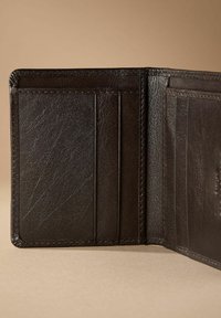 Brown leather wallet interior featuring multiple card slots. Textured surface with precise stitching and a clean, minimal design.