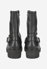 Bottines en cuir noir avec une fermeture éclair sur le côté, un détail de sangle et de bouclerie, et un talon épais. Texture lisse avec des coutures renforcées.