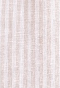 Tissu beige clair avec un motif de rayures verticales texturées et un aspect tissé.